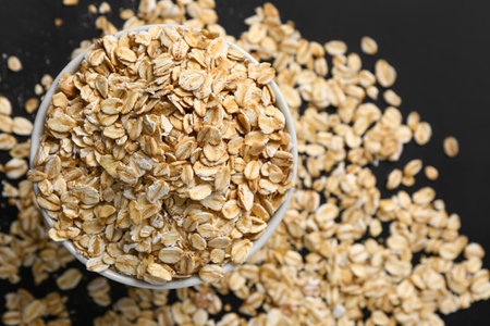 Bowl of raw oatmeal on dark background, closeupの写真素材
