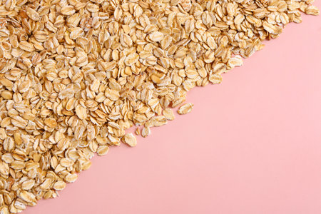Raw oatmeal on pink background, closeup