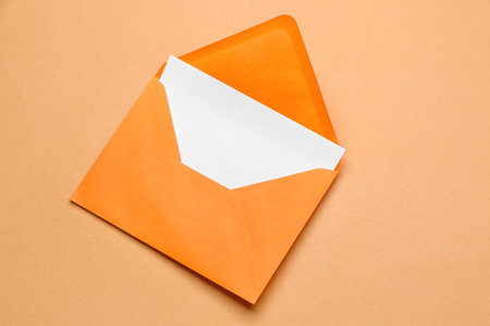 Orange paper envelope with card on color backgroundの写真素材