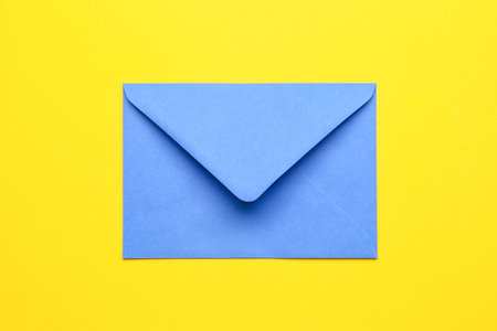 Blue paper envelope on yellow backgroundの写真素材