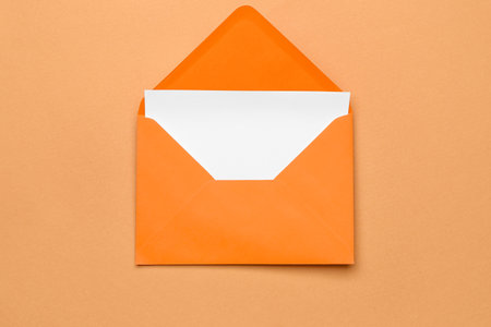 Orange paper envelope with card on color backgroundの写真素材