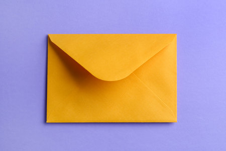 Yellow paper envelope on lilac backgroundの写真素材
