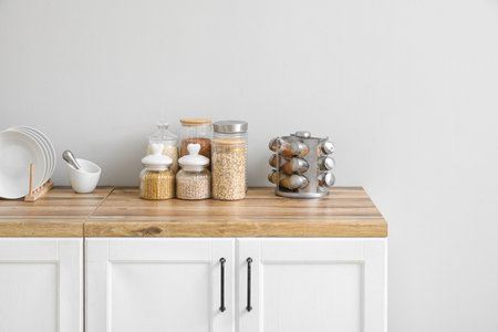 Jars with different cereals and spices on wooden table in kitchen