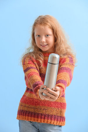 Little redhead girl with bottle on blue backgroundの写真素材
