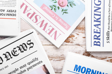Different newspapers on light wooden background, closeupの写真素材