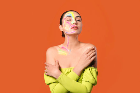 Beautiful young woman with paint on her body against color backgroundの写真素材