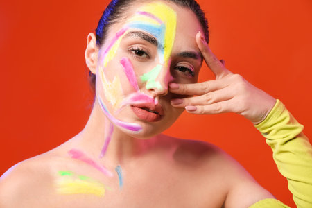 Beautiful young woman with paint on her body against color background