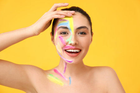 Beautiful young woman with paint on her body against color backgroundの写真素材
