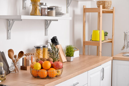 Basket with fresh fruits on wooden table in kitchenの写真素材