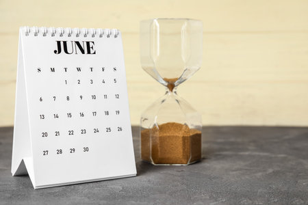 Flip paper calendar with hourglass on tableの写真素材