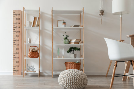 Book shelves with decor and stadiometer near light wallの写真素材