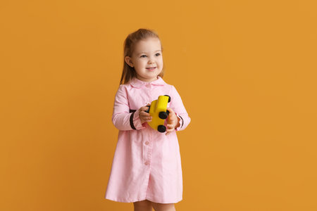 Cute little girl with toy car on color backgroundの写真素材