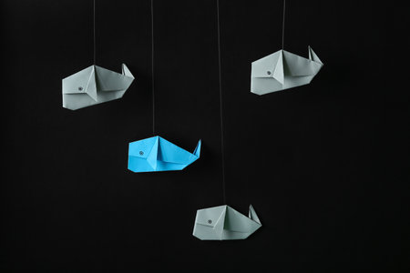 Origami whales on dark background. concept of uniqueness