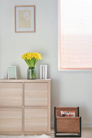 Modern chest of drawers with decor near light wall in room