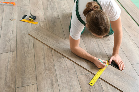 Carpenter taking measurements of laminate flooring in roomの写真素材