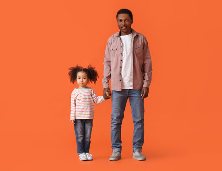 Portrait of happy African-American father and his little daughter on color backgroundの写真素材