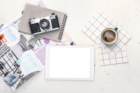Composition with cup of coffee, tablet computer, notebooks and photo camera on light background