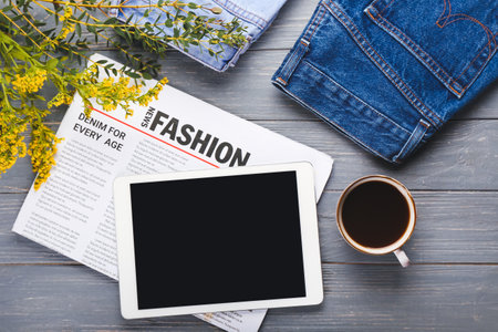 Composition with cup of coffee, tablet computer, newspaper and jeans on wooden backgroundの写真素材