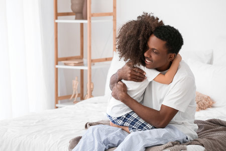 Portrait of happy African-American father and his little daughter hugging at homeの写真素材