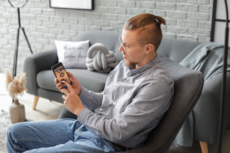 Man with mobile phone using smart home security system applicationの写真素材