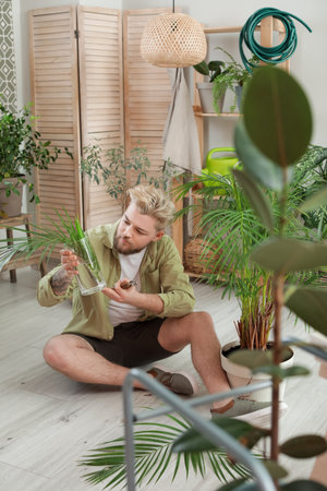 Young man taking care of plants at homeの写真素材