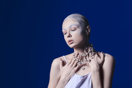 Beautiful young woman with dyed eyebrows and necklace on color backgroundの写真素材