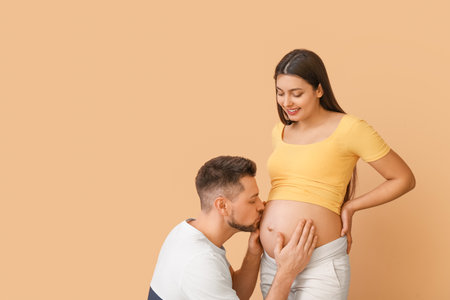Beautiful pregnant couple on color background