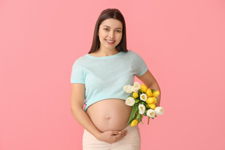 Young pregnant woman with beautiful flowers on color backgroundの写真素材
