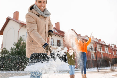 Family removing snow outdoors on winter dayの写真素材