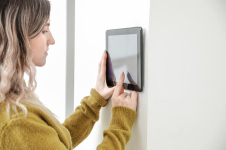 Woman using smart home security system control panelの写真素材