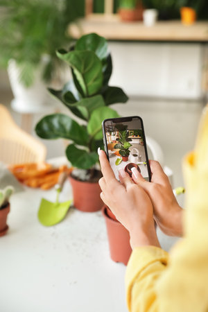 Young woman taking photo of her plants at home