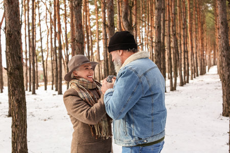 Happy mature couple in forest on winter dayの写真素材