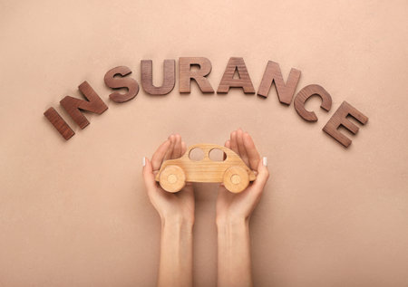 Woman with wooden car and word INSURANCE on color backgroundの写真素材