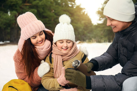 Happy family drinking hot tea in park on winter dayの写真素材