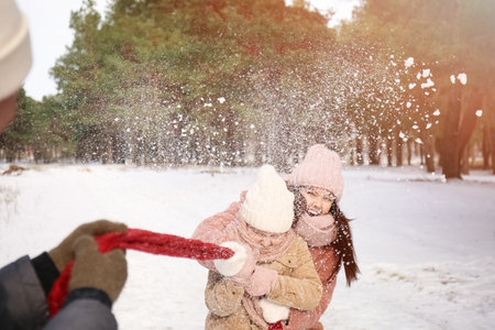 Happy family playing in park on winter dayの写真素材