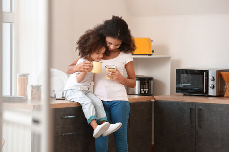 Cute African-American sisters drinking tea at homeの写真素材