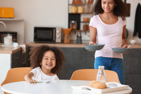 Cute African-American sisters having breakfast at homeの写真素材