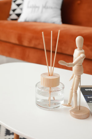 Reed diffuser and wooden mannequin on table in room
