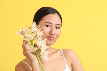 Young woman with orchid flowers on color backgroundの写真素材
