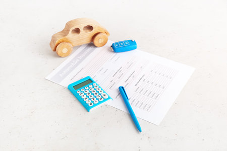 Automobile insurance with calculator and car figure on white backgroundの写真素材