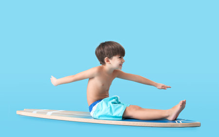 Cute little boy with surfboard on color background