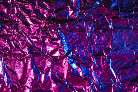 Shiny crumpled foil in neon light as backgroundの写真素材