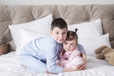 Cute little children sitting on bedの写真素材