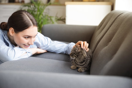 Beautiful young woman with cute cat at homeの写真素材