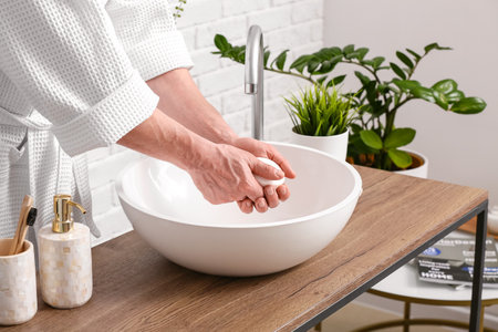 man washing hands in bathroomの写真素材