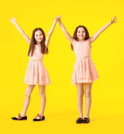Portrait of cute twin girls on color backgroundの写真素材