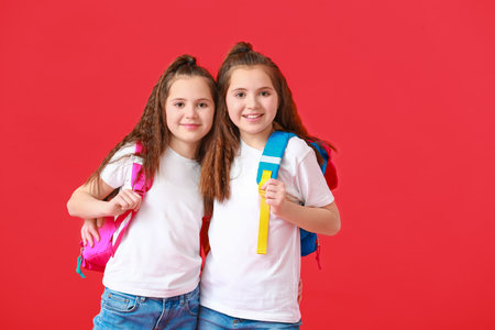 Portrait of cute twin school girls on color backgroundの写真素材