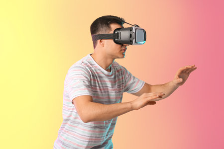 Young man with virtual reality glasses on color background