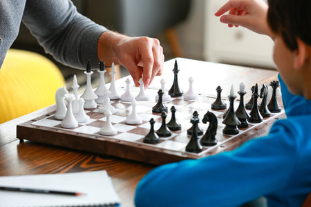 Father and son playing chess at home, closeup