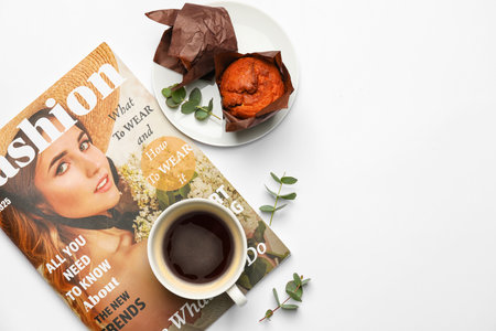 Cup of coffee with magazine on white background